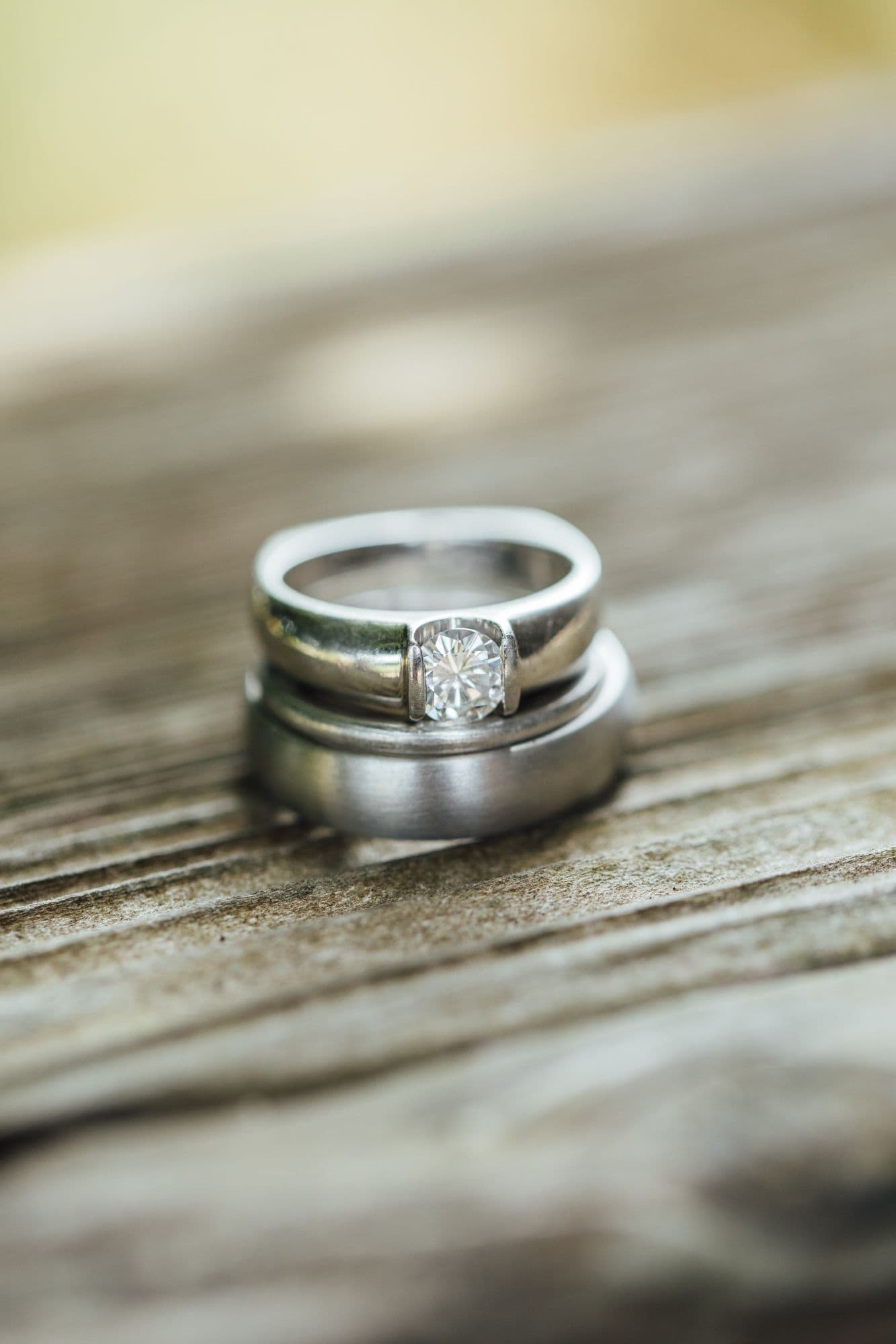 Wedding band and solitaire ring resting on weathered wood