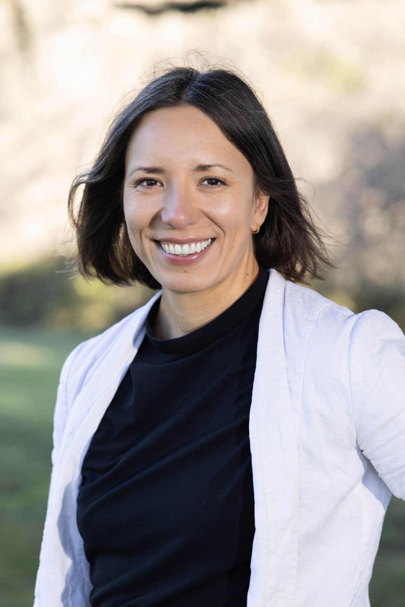 Outdoor headshot of a woman in a white shirt with a park behind her