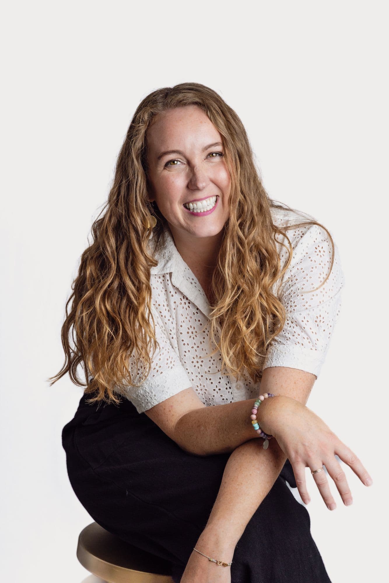 Seated studio headshot of a woman in a white eyelet blouse