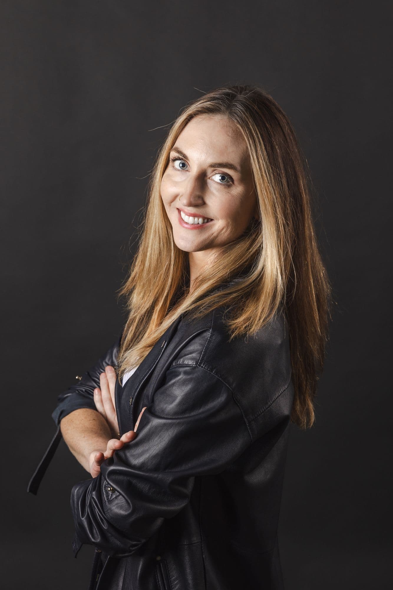 Studio headshot of a woman in a leather jacket against a charcoal background