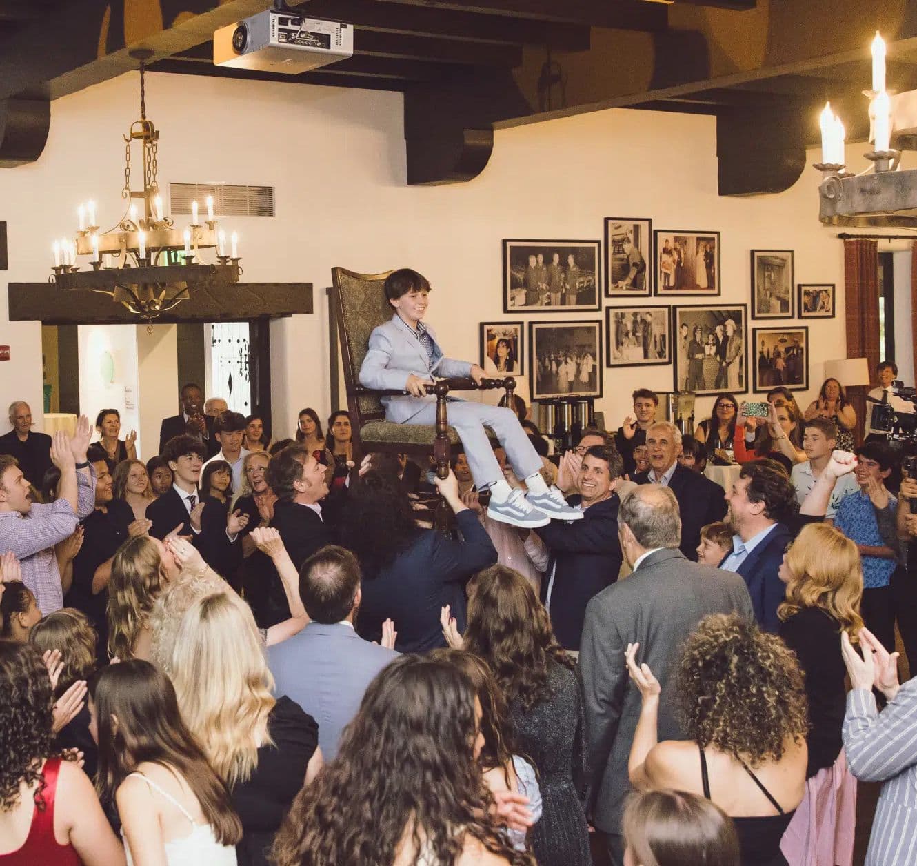 Guests lifting a boy in a chair on the dance floor at a reception