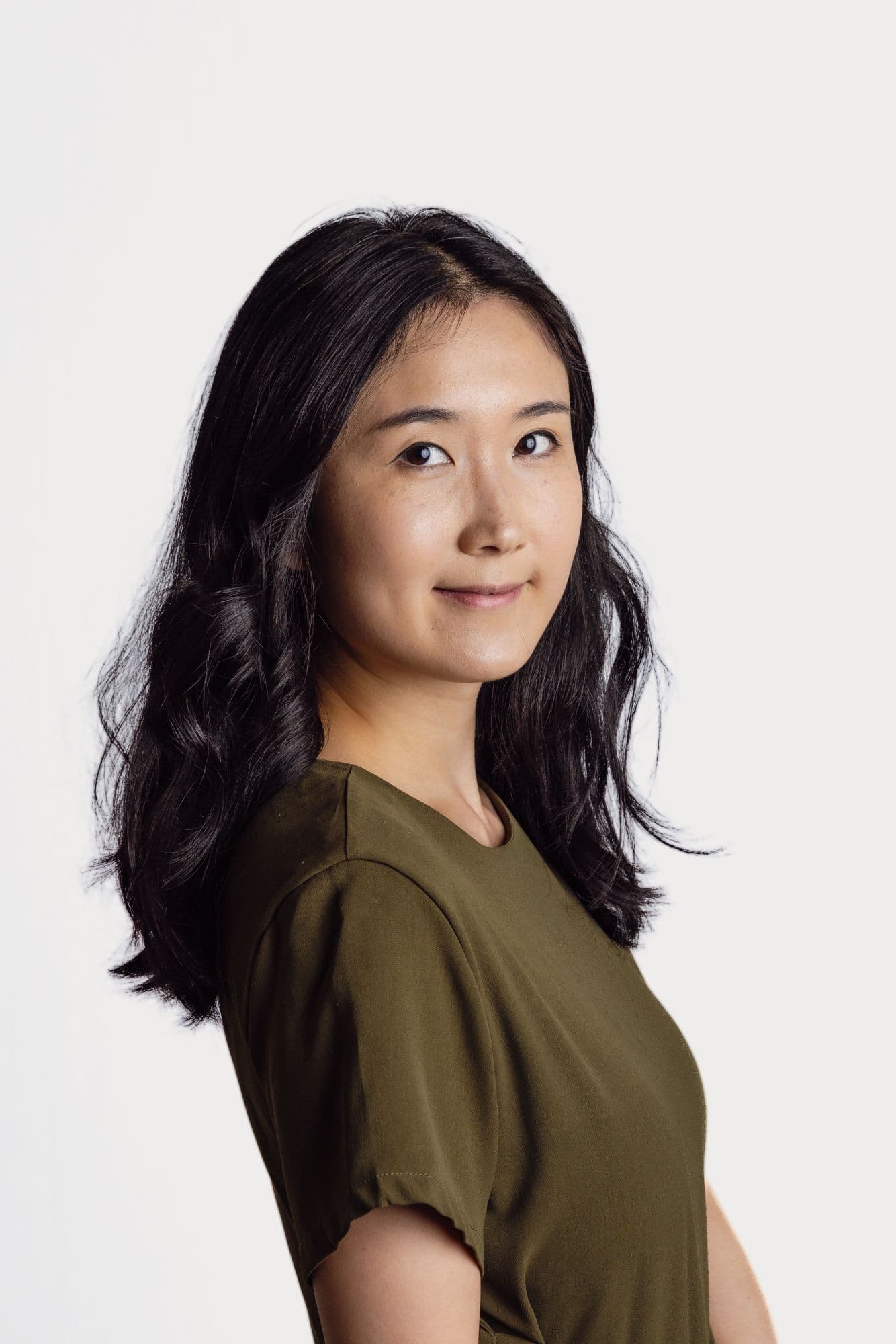 Studio headshot of a woman in an olive top, turned in profile