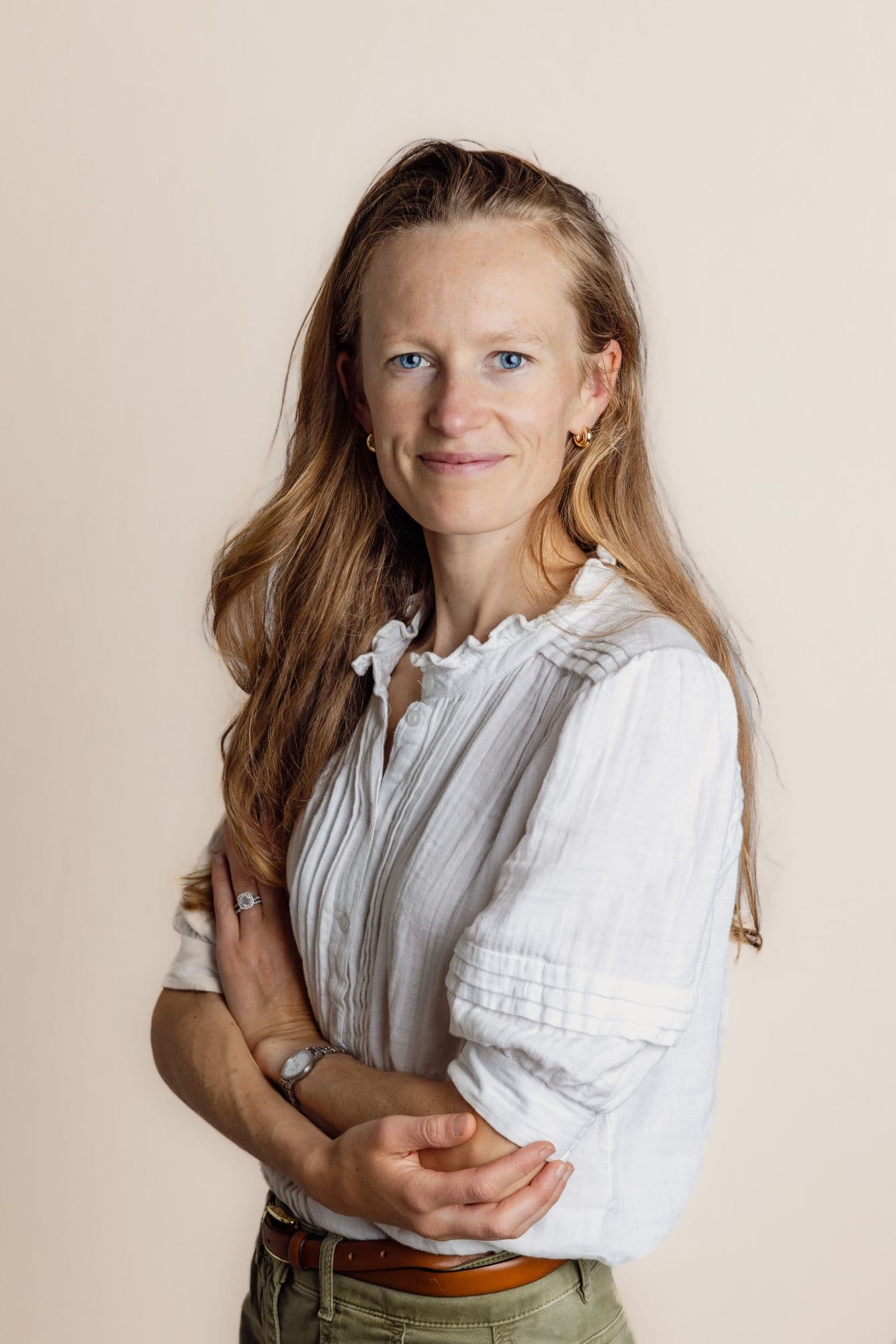 Studio headshot of a woman in a white linen blouse against a warm backdrop