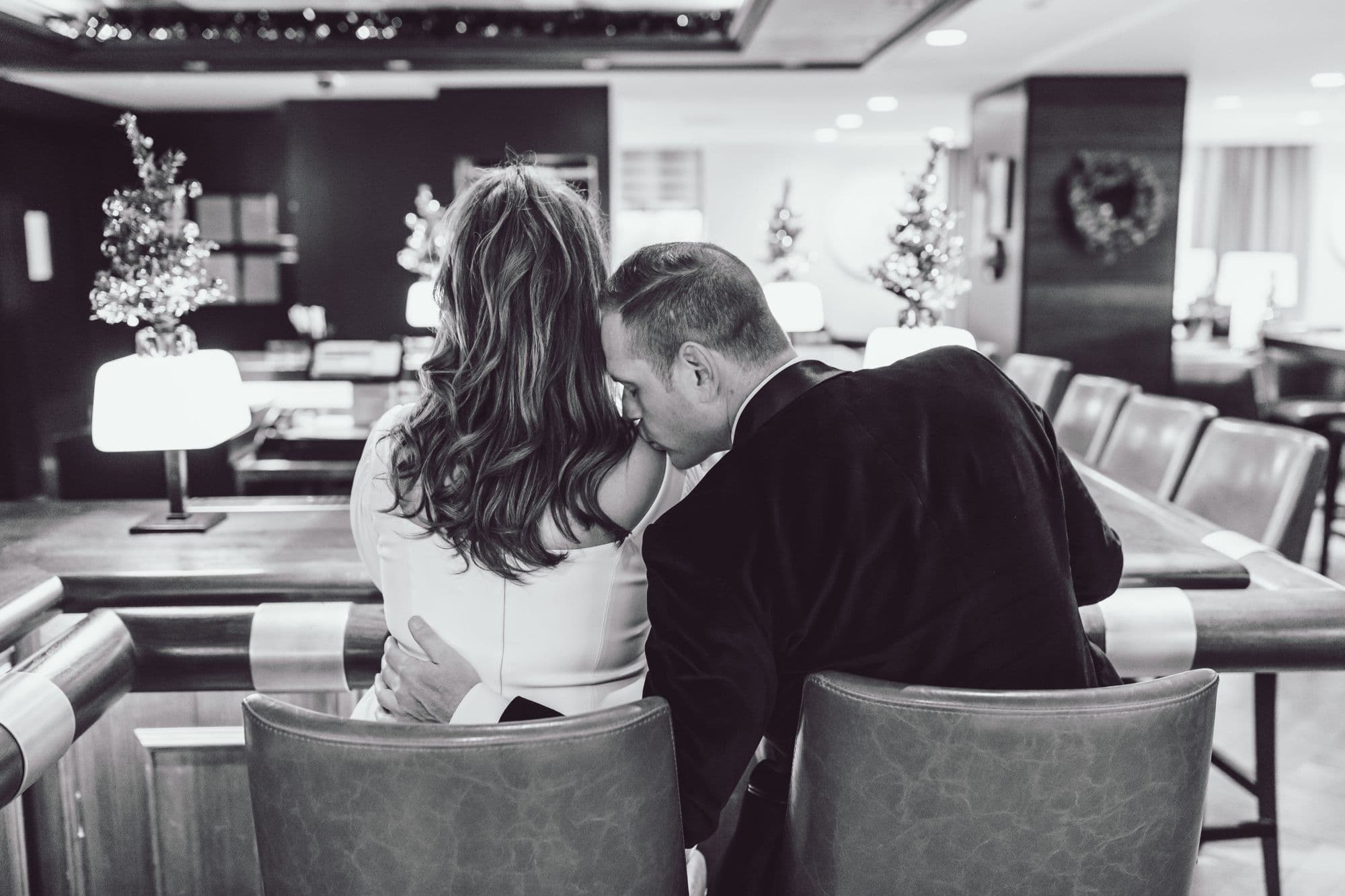 Couple leaning close together in a hotel lobby, black and white