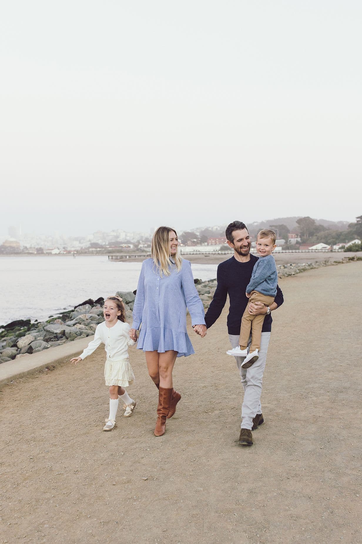 Family of four walking a bayside path, the youngest carried
