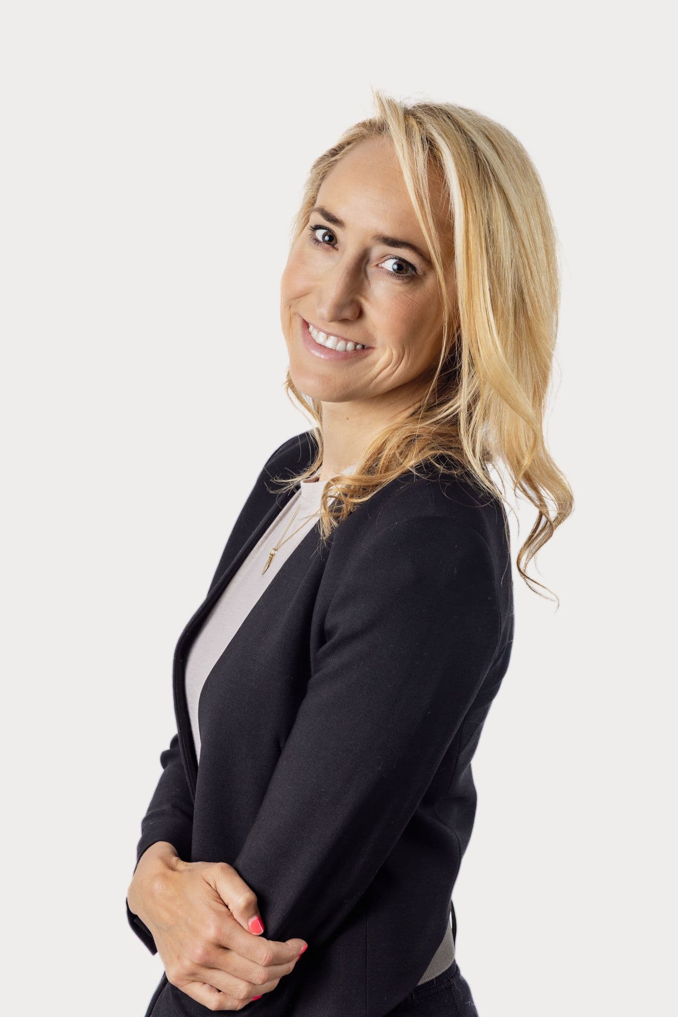 Studio headshot of a woman in a navy blazer, turned toward the camera