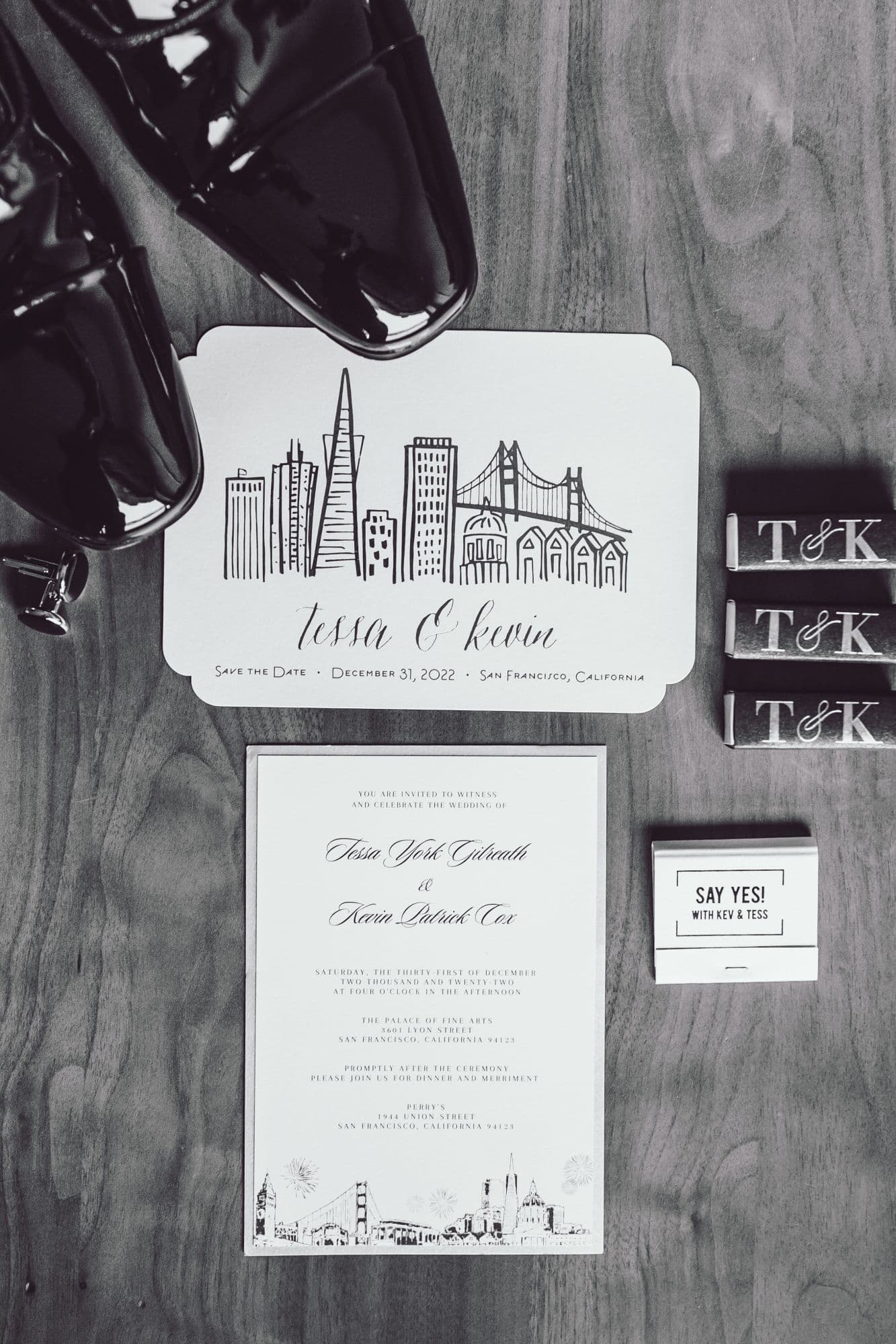 Wedding invitation suite and patent shoes laid out on a wood floor